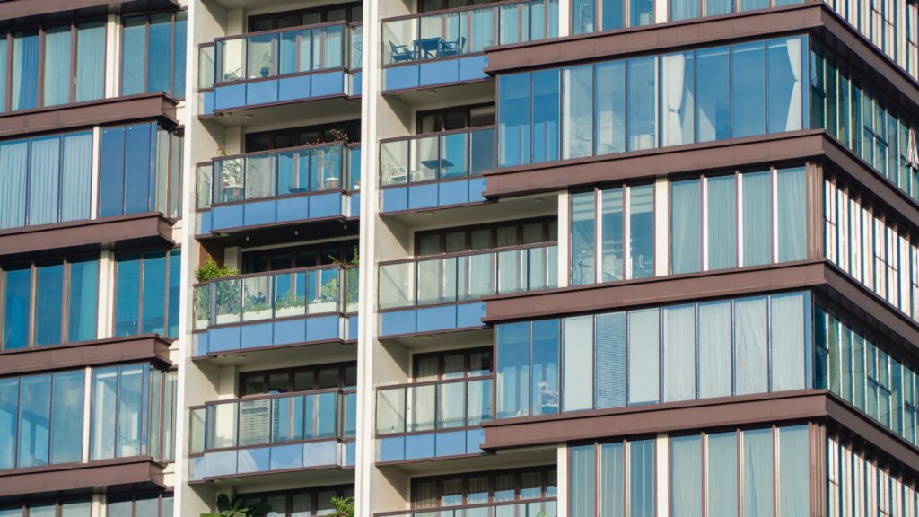 Close-up view of a modern glass apartment facade with balconies, representative of contemporary residential architecture in Dubai Creek Harbour where Surf at Creek Beach is located