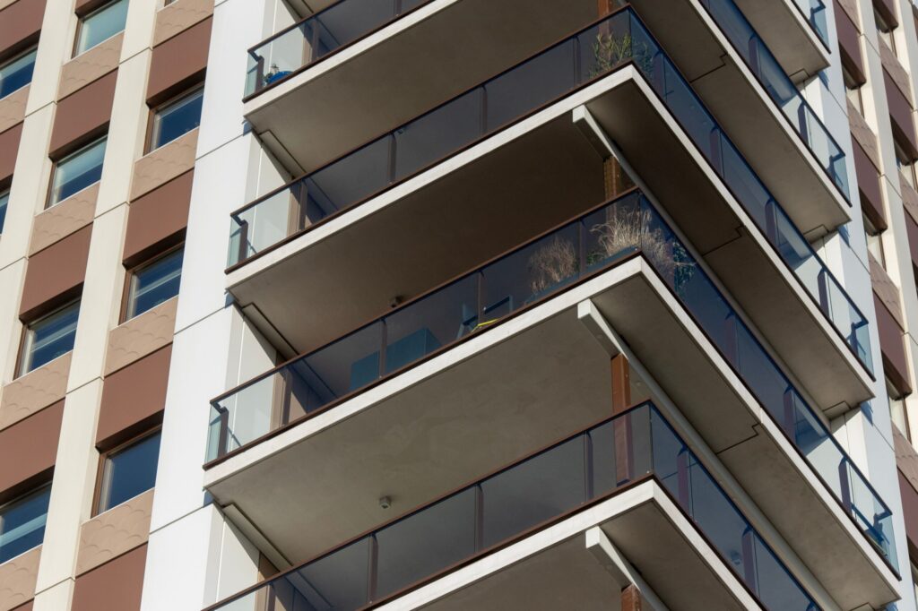 Close-up view of a modern high-rise building's cantilevered glass balconies against a clear sky, Business Bay