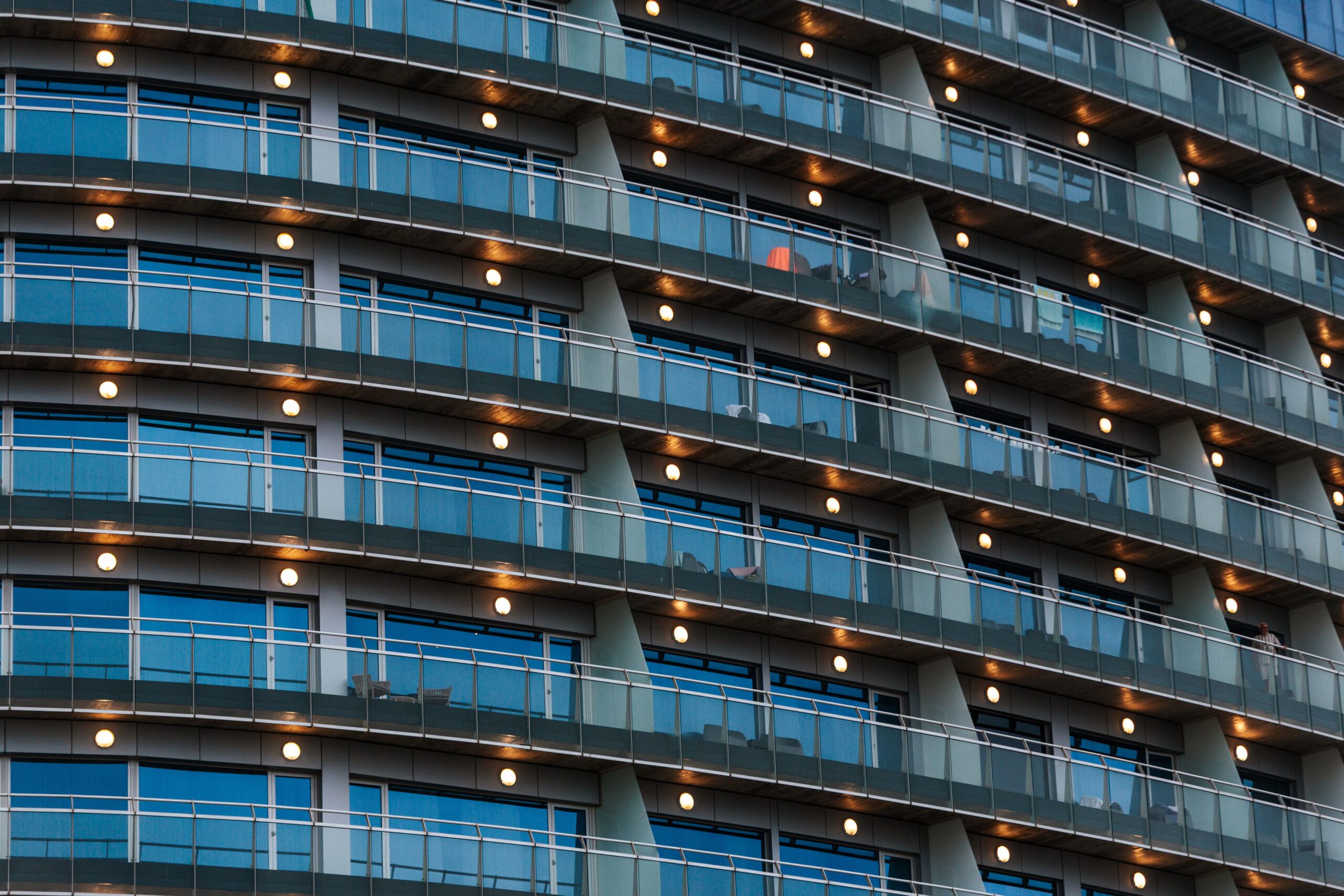Close-up of a modern curved high-rise facade with lit balconies at dusk, in the architectural style found across Dubai Marina's newer waterfront towers