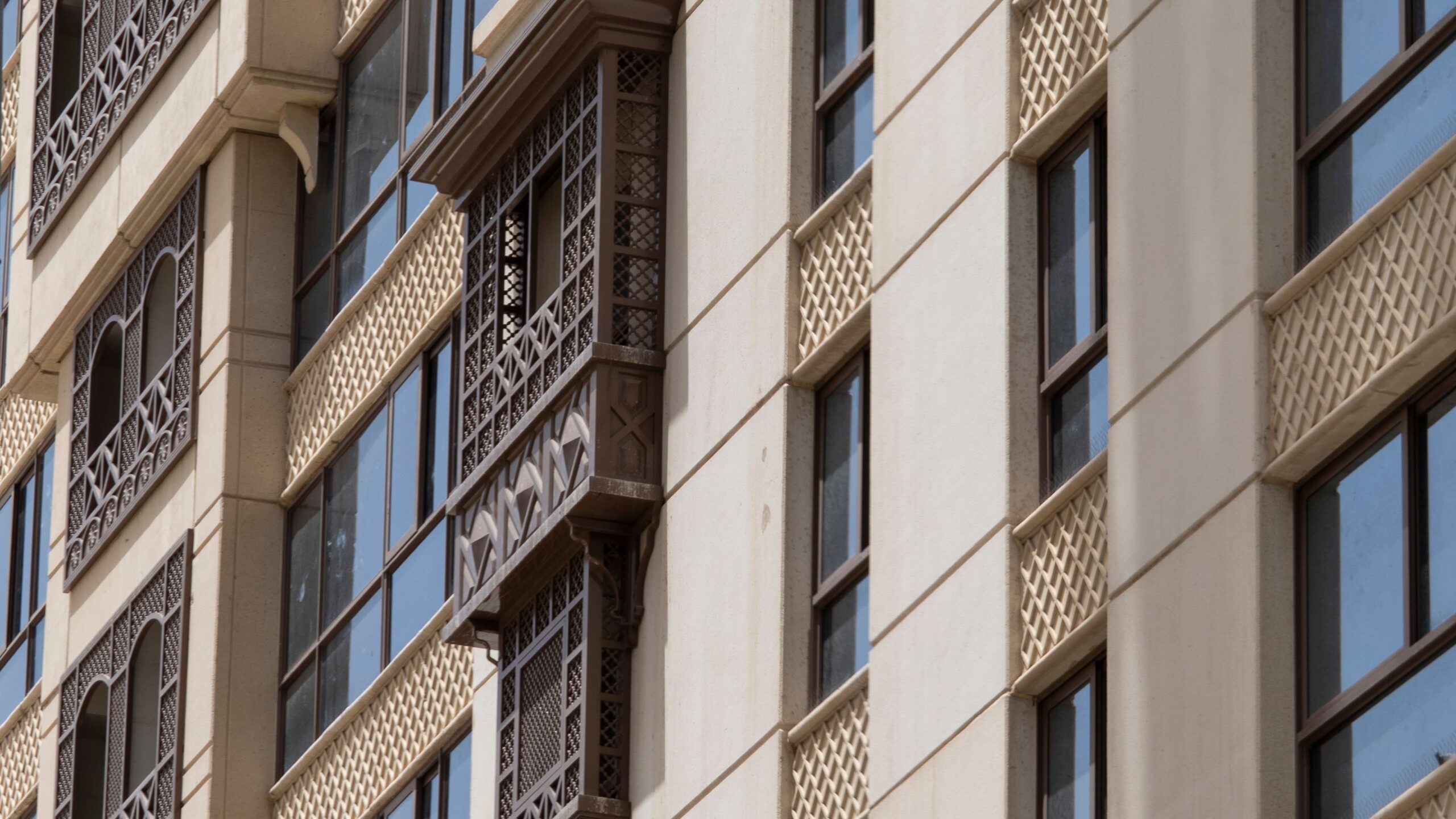 Cream facade with intricate Arabic-style mashrabiya latticework balcony detail on a Dubai residential building, representative of Phoenix Tower in DubaiLand Residence Complex, Dubai