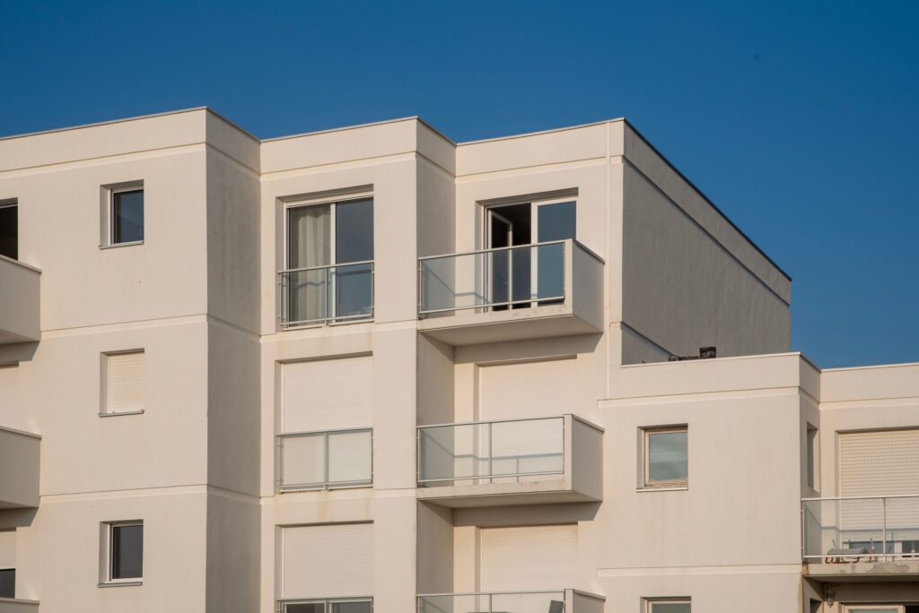 Clean white modern apartment building corner against a clear blue sky, representative of Belgravia Square's contemporary low-rise architecture in JVC, Dubai