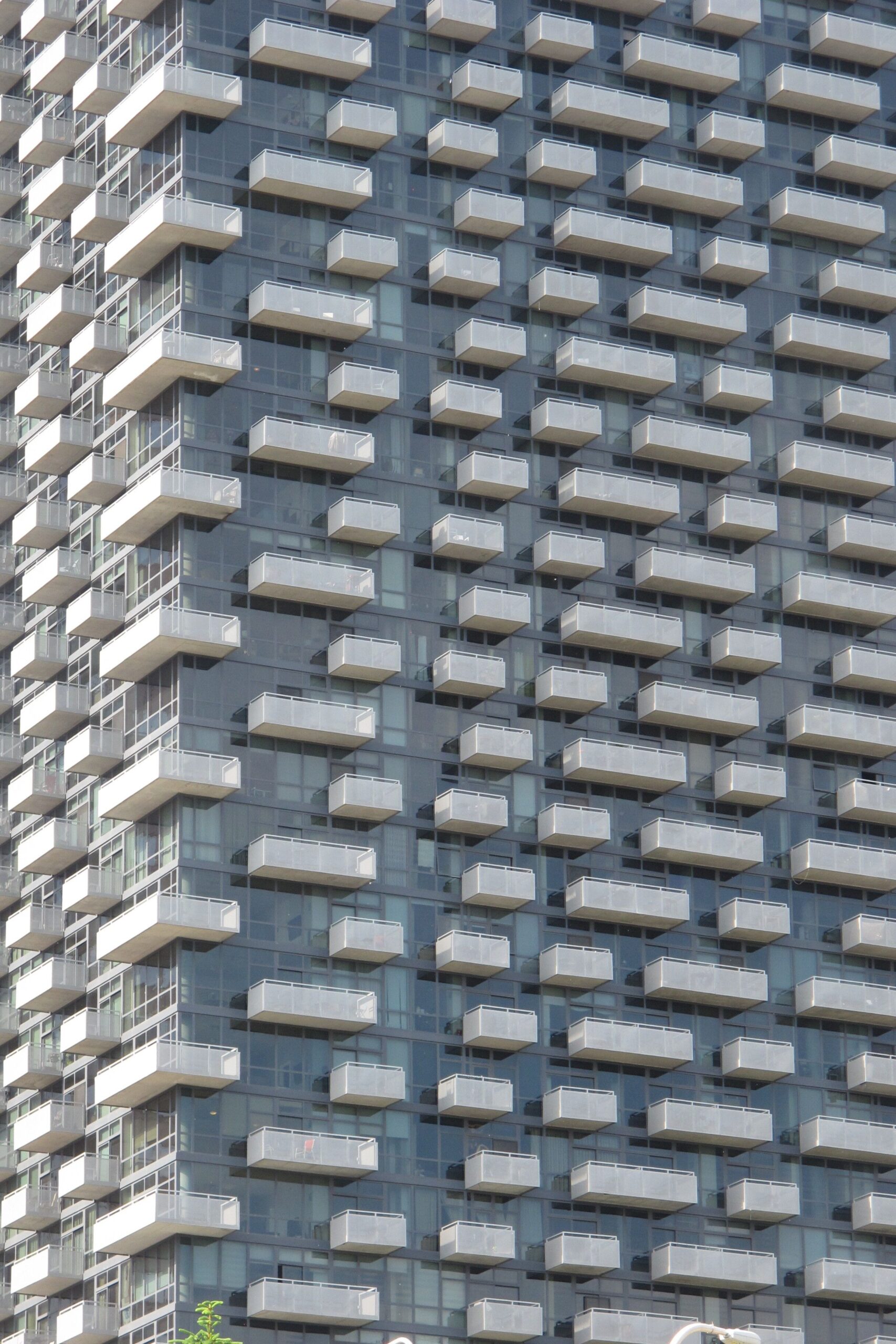 Modern glass-facade high-rise apartment building with repeating white balconies, representative of contemporary Dubai Hills Estate architecture