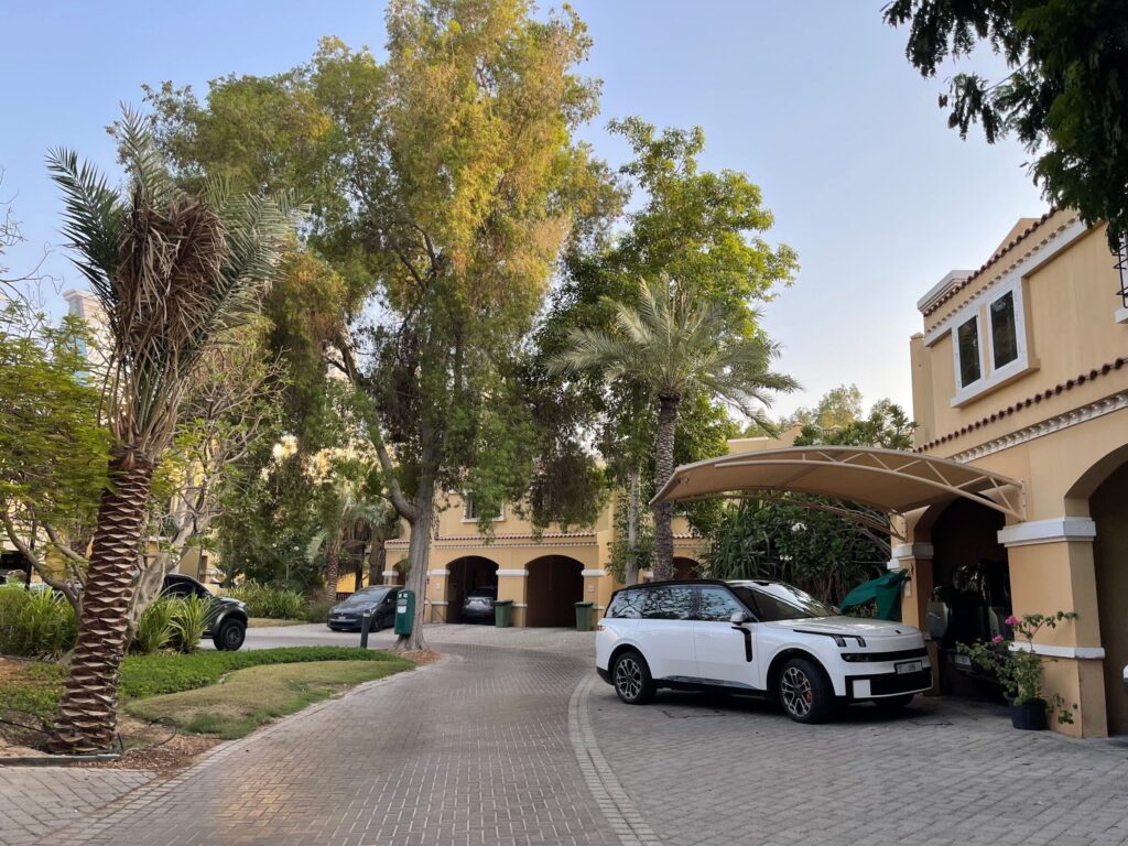 Cream Mediterranean-style Dubai villa with an arched carport and palm trees near Indigo Ville 8, JVC