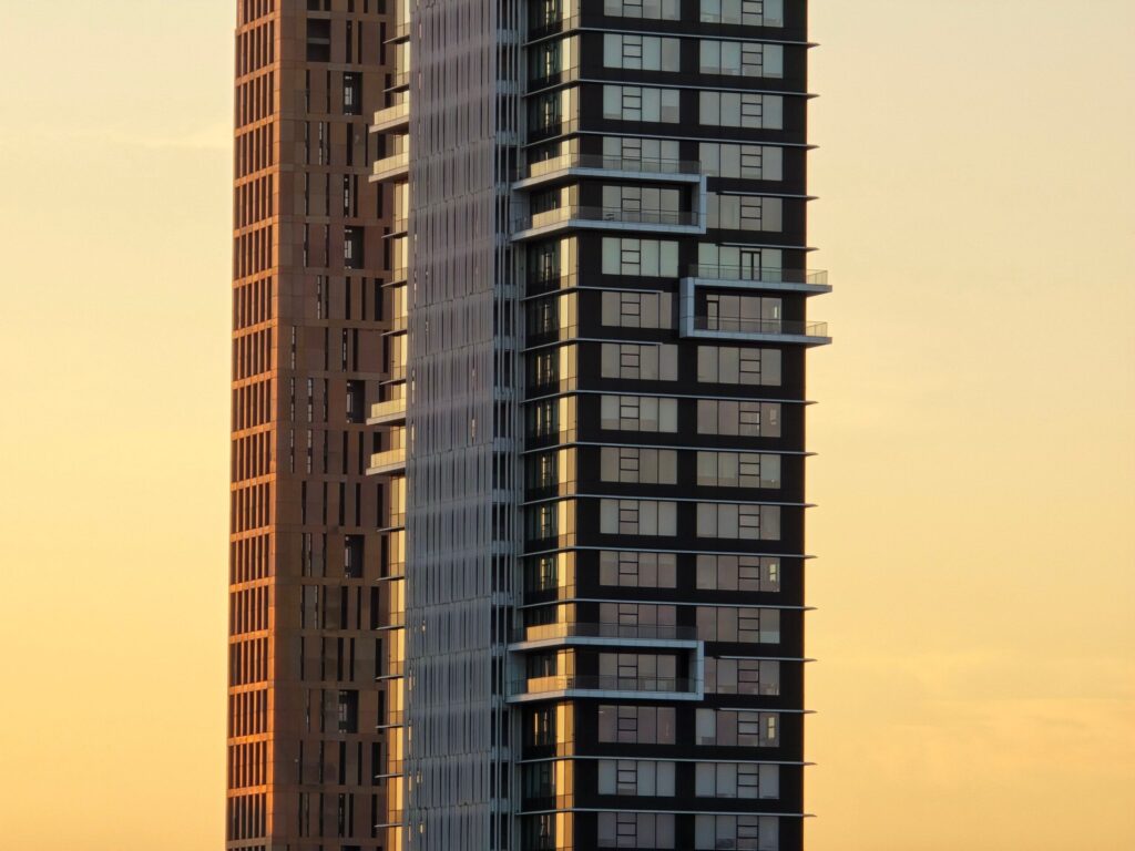 Tall Dubai residential tower with a glass and stone facade at sunset