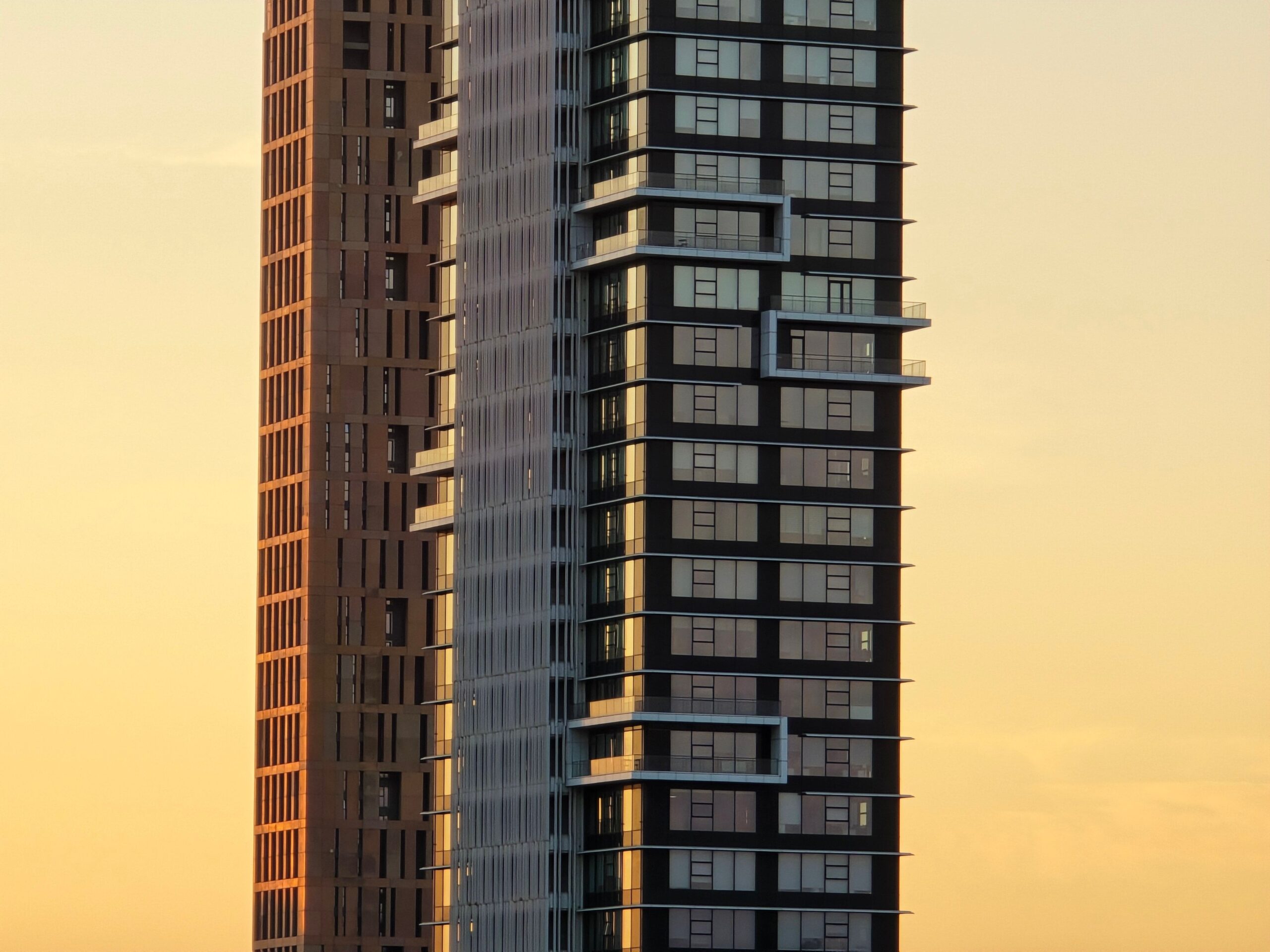 Tall Dubai residential tower with a glass and stone facade at sunset