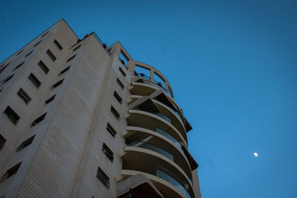 Low-angle view of a white apartment building with curved balconies under a blue sky