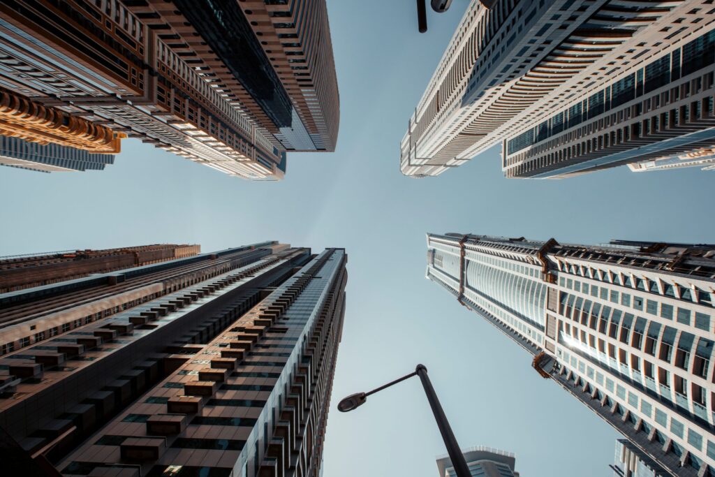 Low angle view looking up at modern high-rise residential buildings against a clear blue sky, representative of Ruby Residence in Dubai Silicon Oasis, Dubai
