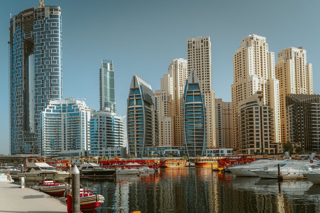 Daytime view of Dubai Marina waterfront towers and moored boats under a clear blue sky