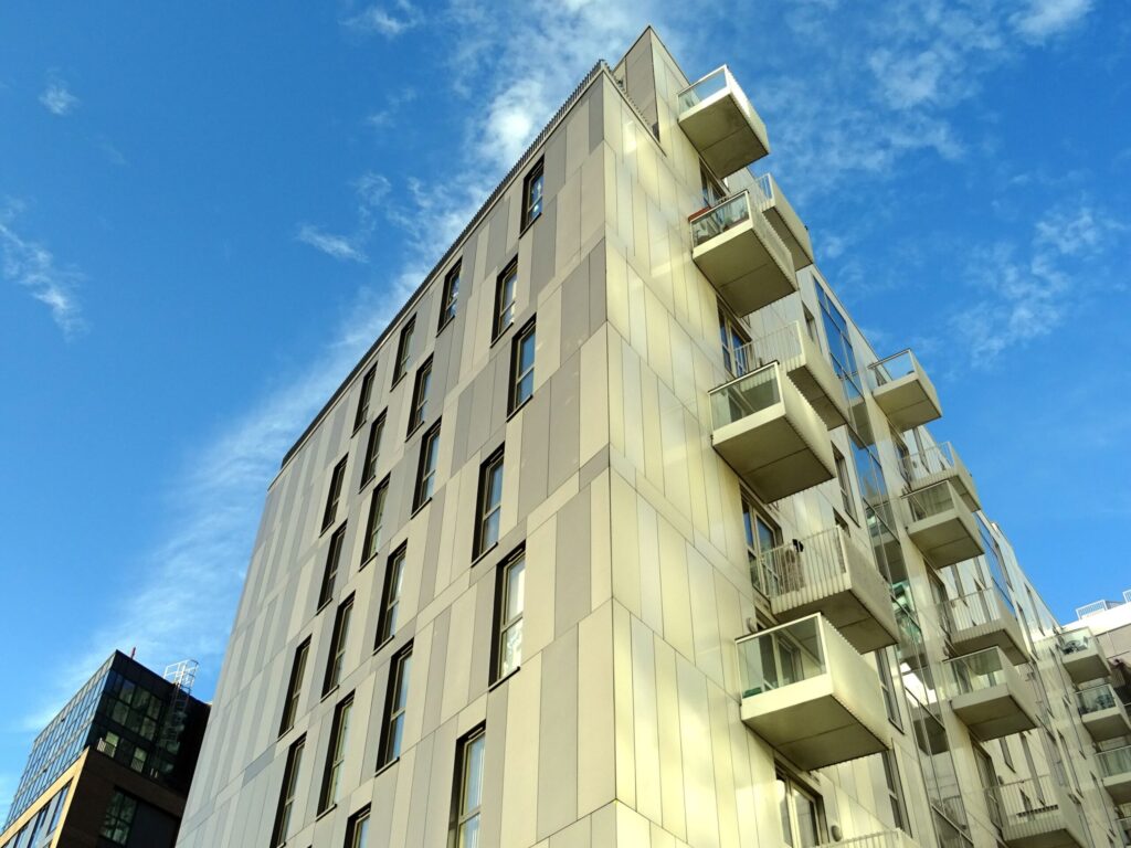 Low angle view of a modern cream apartment building corner with box balconies against a clear blue sky in Dubai