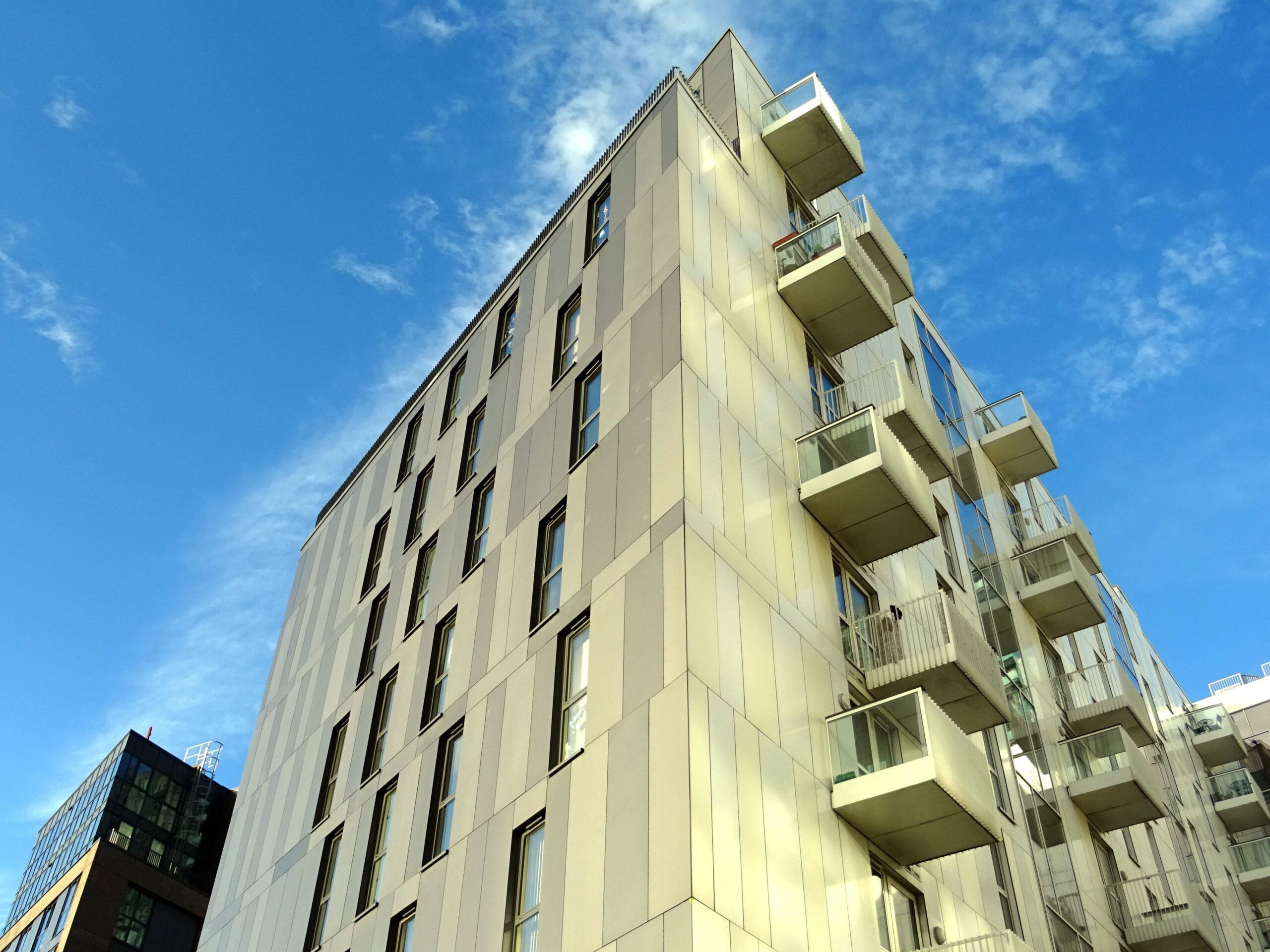 Low angle view of a modern cream apartment building corner with box balconies against a clear blue sky in Dubai