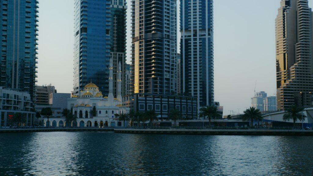 Skyscrapers and a mosque by the Dubai Marina waterfront on a clear day