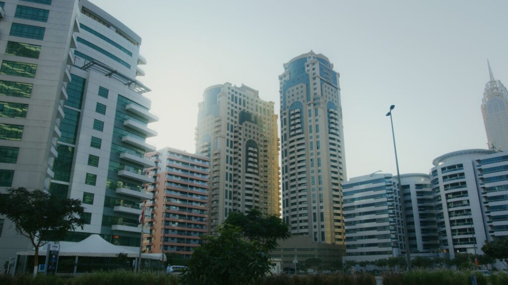 Low-angle view of modern high-rise residential towers with tiered balconies against a hazy blue sky, Business Bay, Dubai