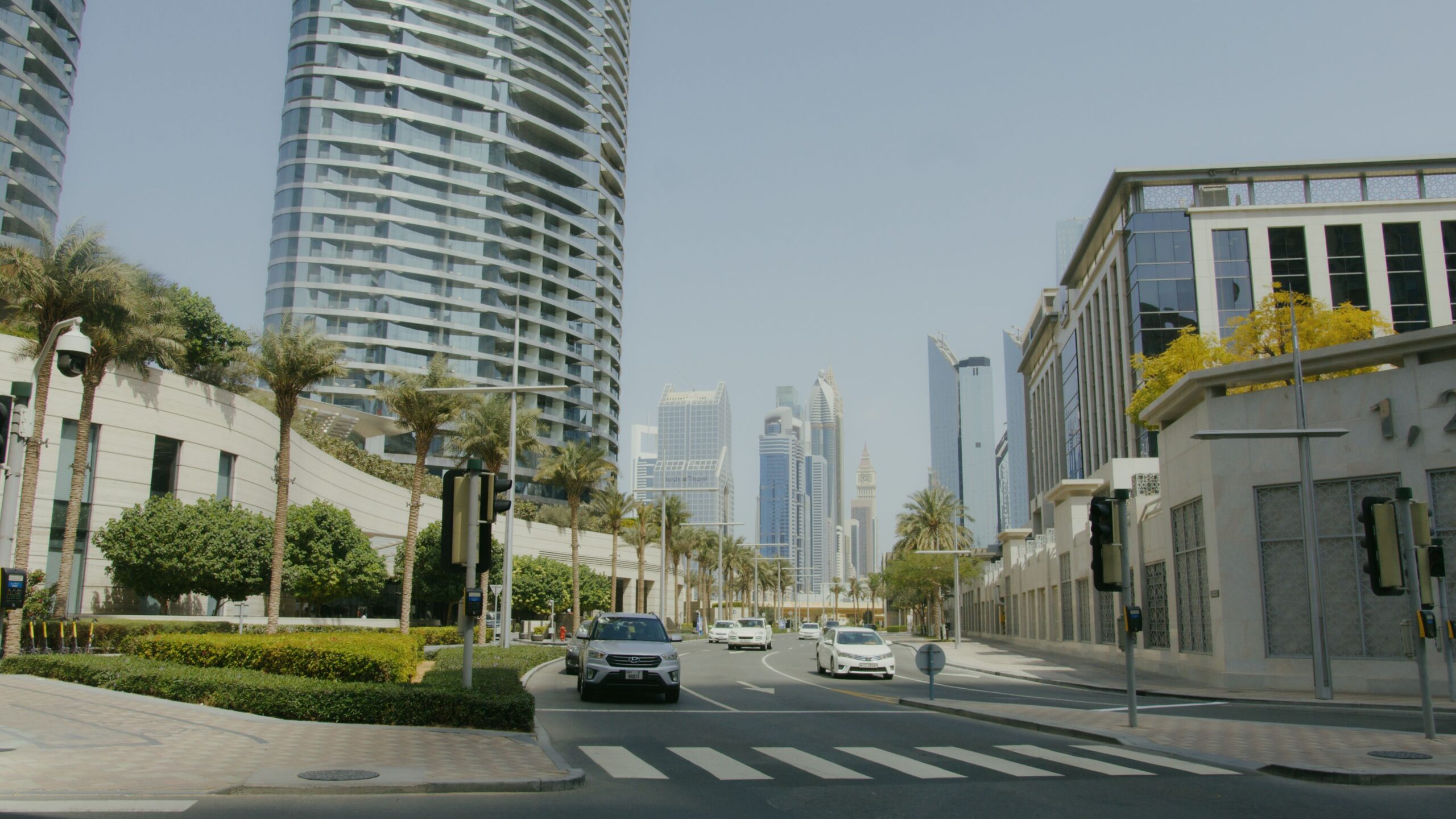 Palm-lined Dubai boulevard with a residential tower and city skyline in the distance, near Imperial Building, Dubai Silicon Oasis