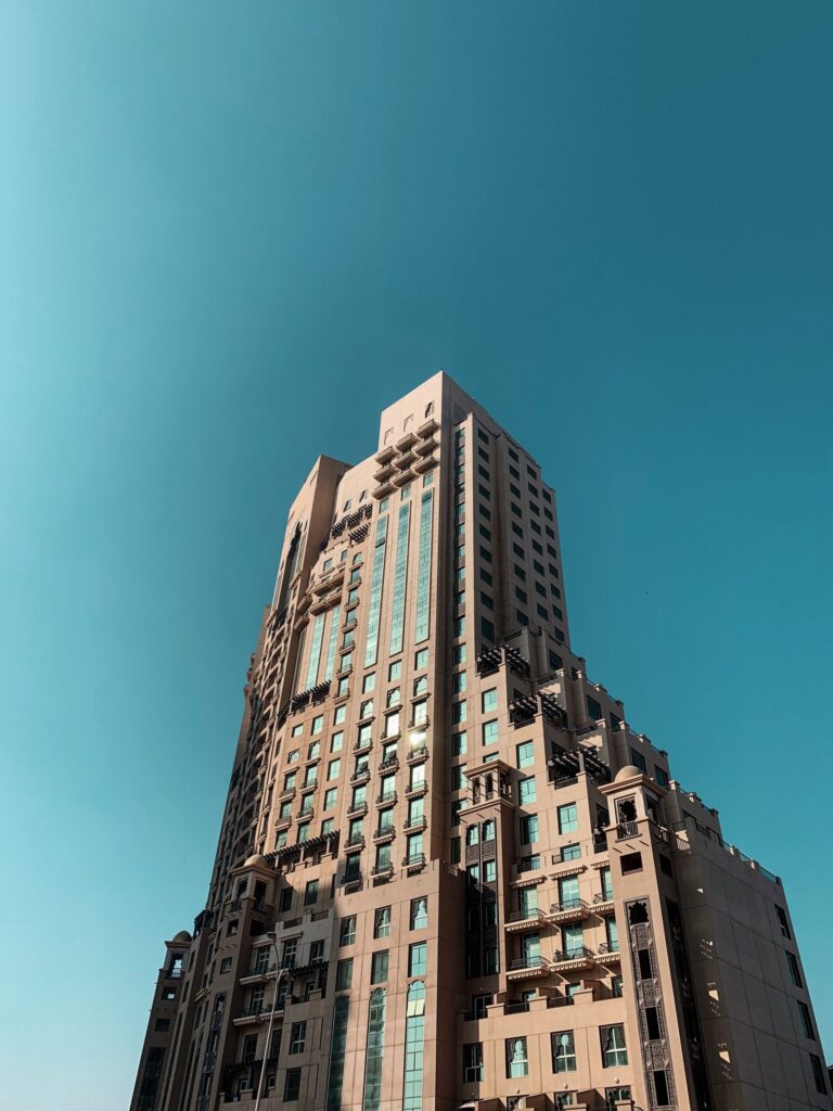 Beige stone-clad Dubai tower with arched windows and ornamental balconies against a clear blue sky