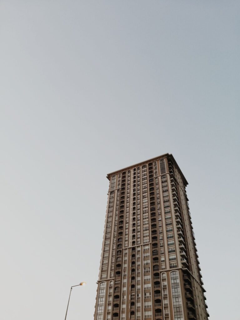 Low-angle view of a tall Dubai residential apartment tower with balconies against a clear sky