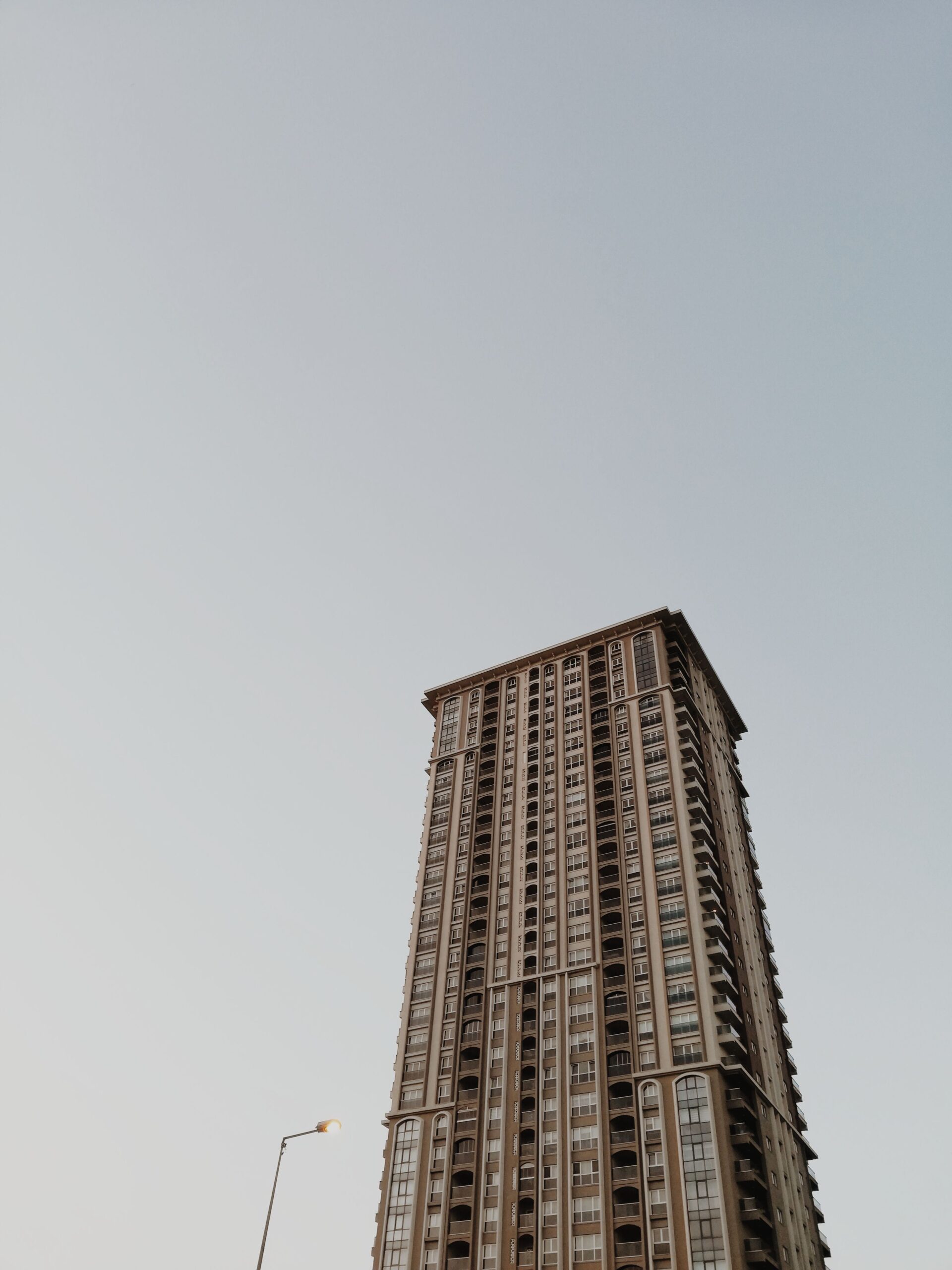 Low-angle view of a tall Dubai residential apartment tower with balconies against a clear sky