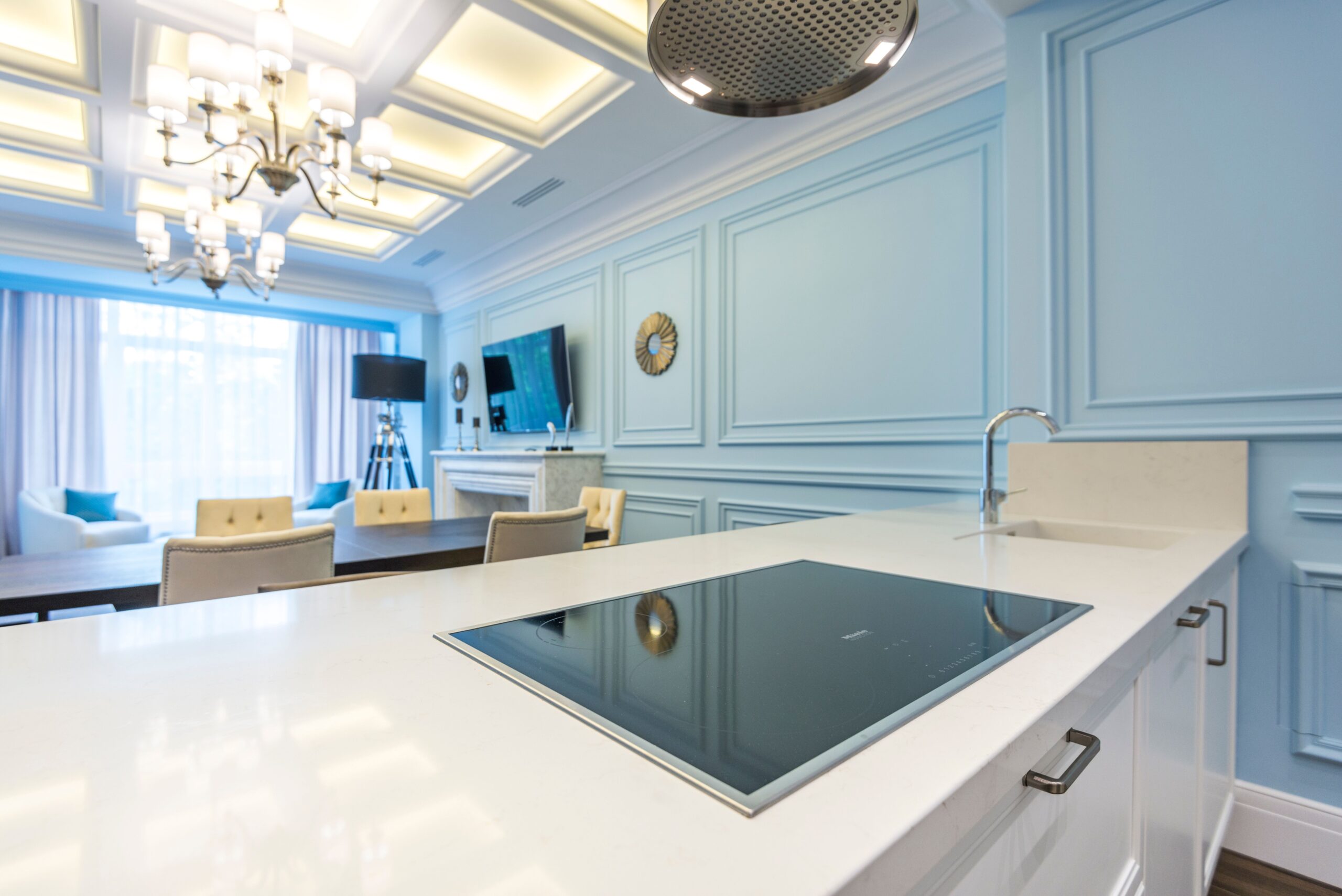 Modern open-plan apartment kitchen and living interior with pale blue panelled walls in Dubai