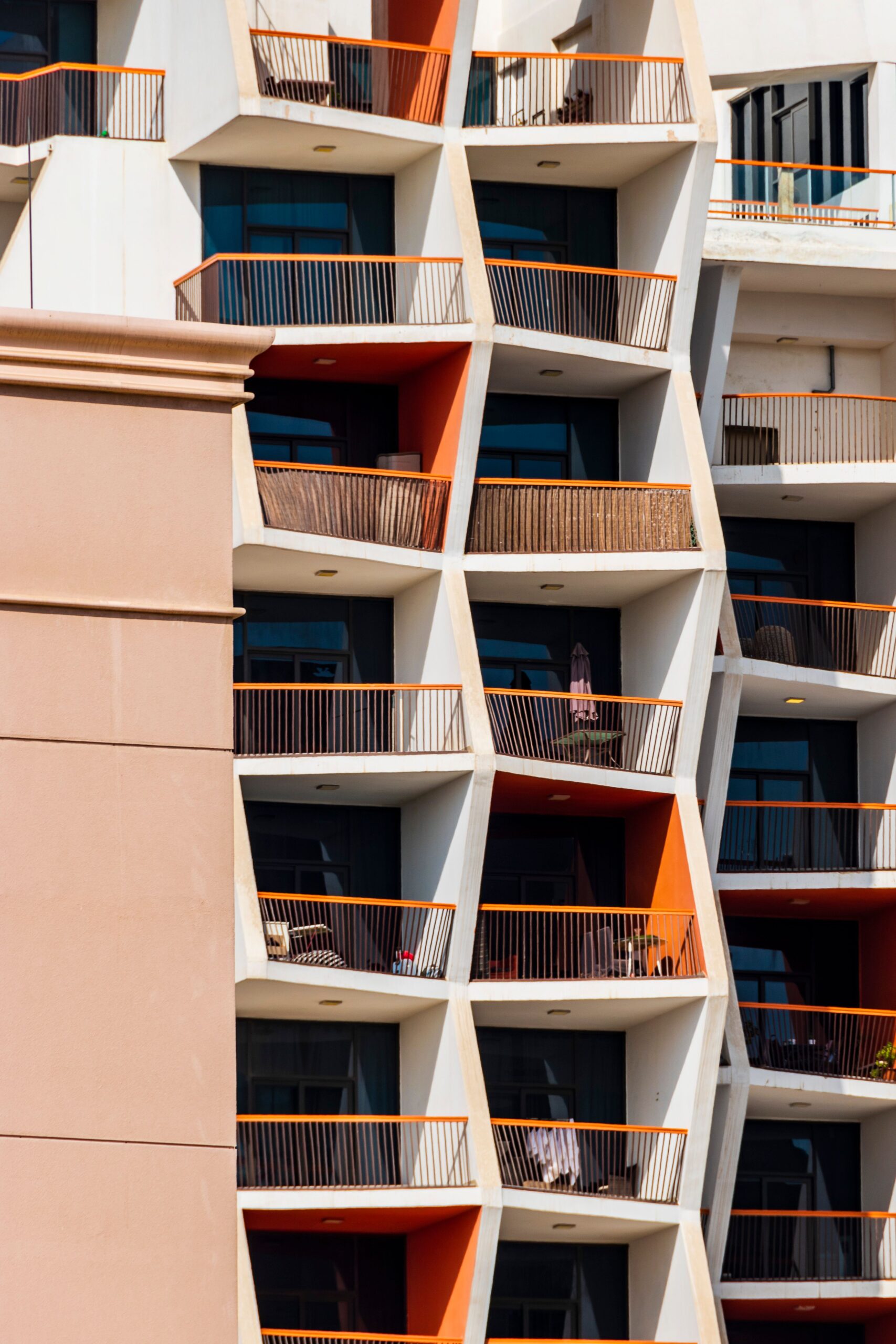 Modern Dubai apartment building with angular white balconies and orange accents against a clear sky