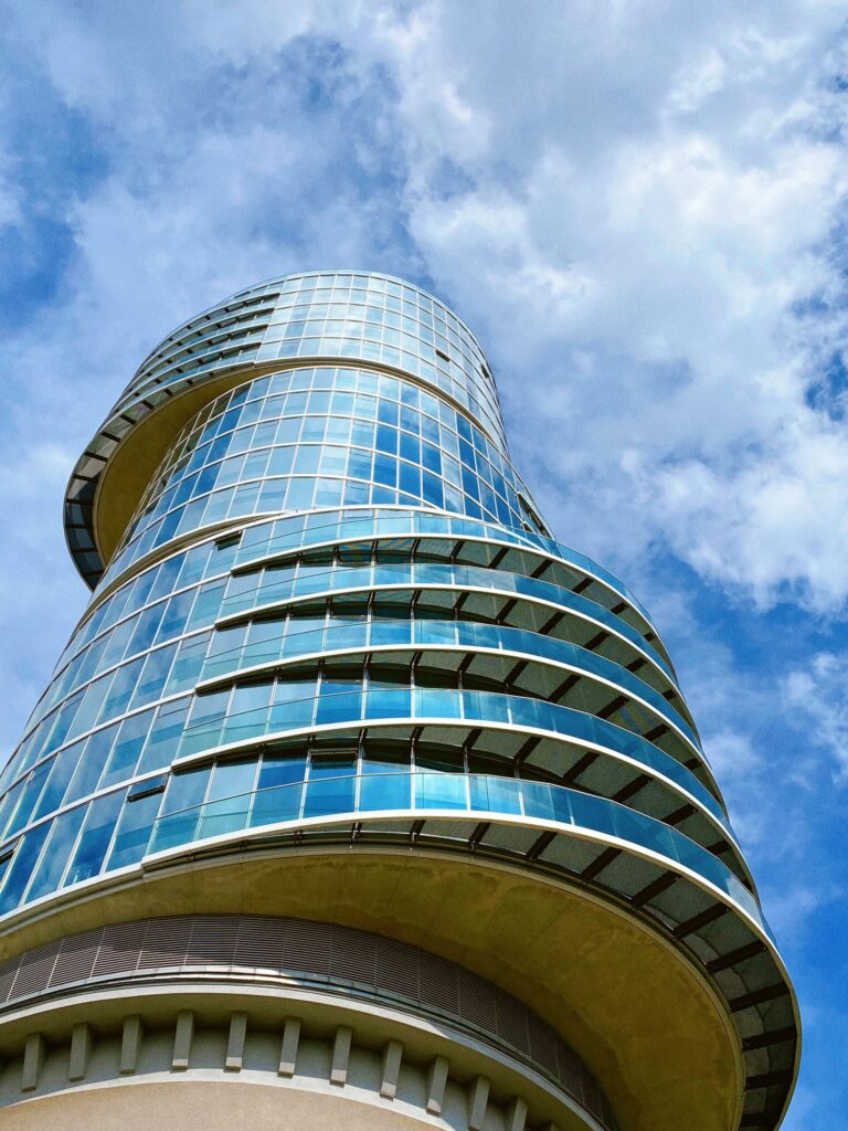 Curved modern glass residential tower against a blue sky near Neva Residences, JVC