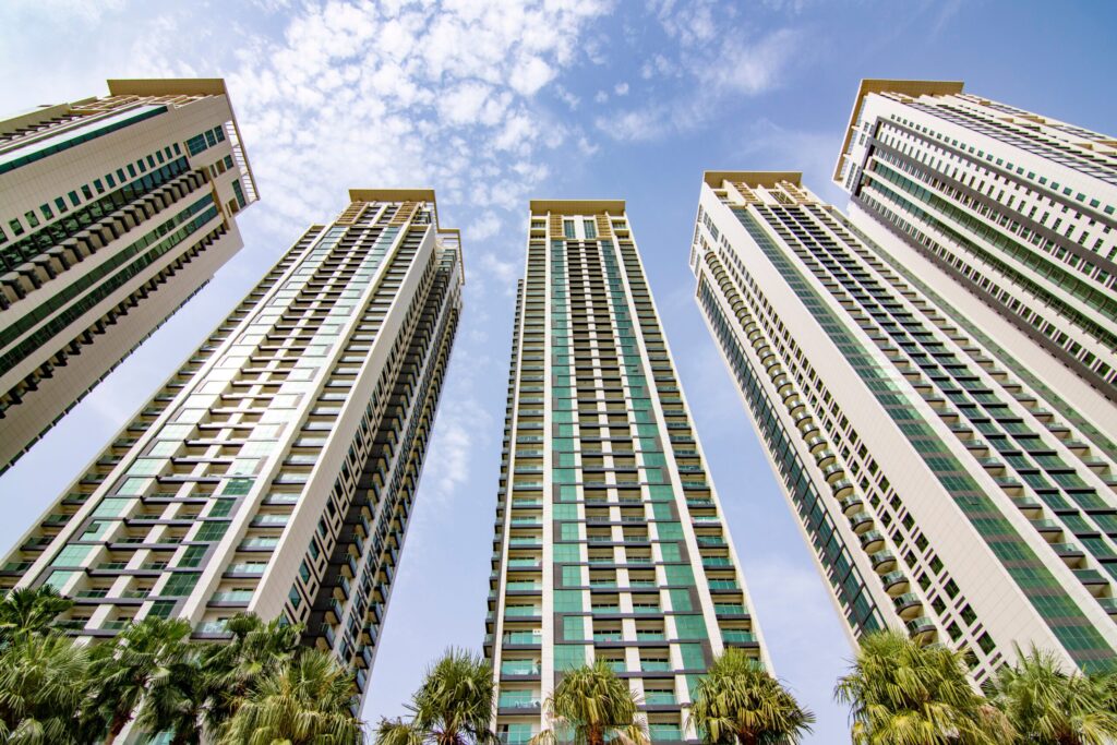 Residential towers seen from below with palm trees against a blue sky