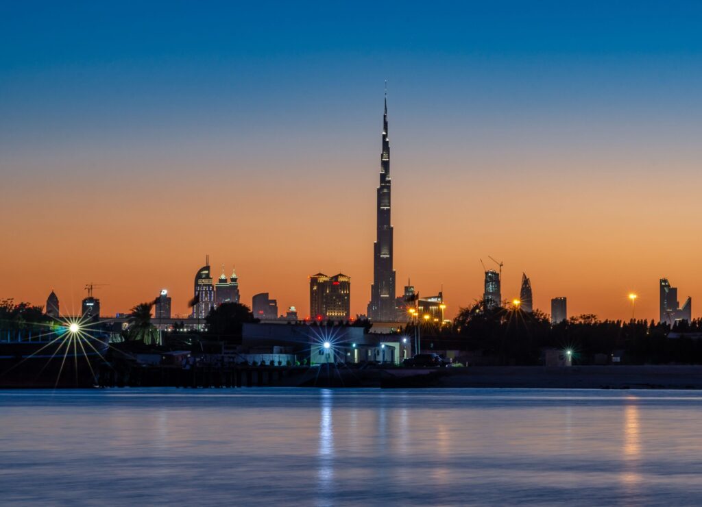 Sunset silhouette of the Burj Khalifa and Downtown Dubai skyline reflected on a waterfront near Fountain Views