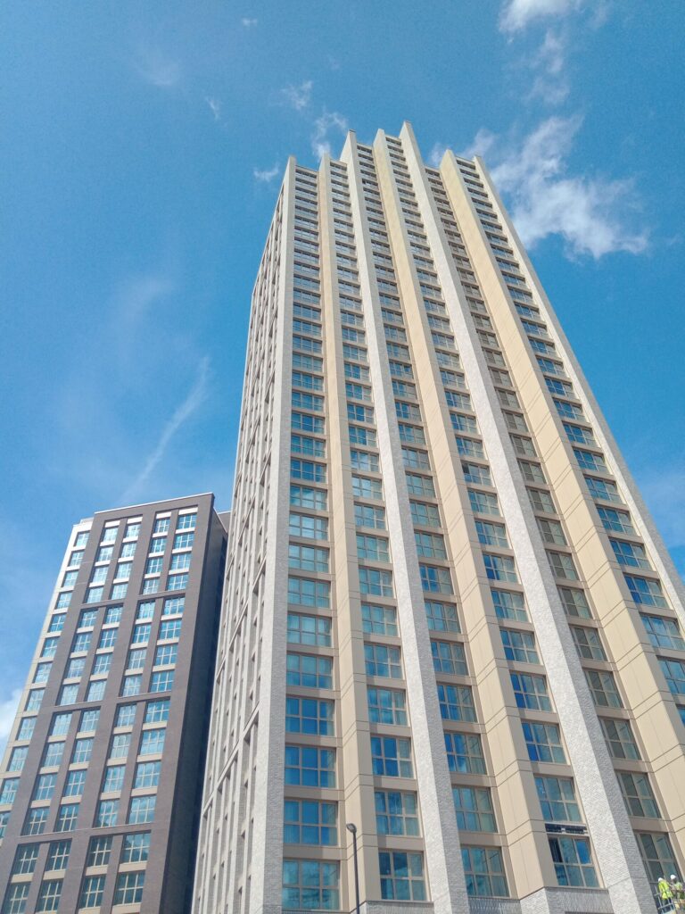 Low angle view of a modern high-rise apartment tower against a clear blue sky, representative of Palacio Tower in Dubai Silicon Oasis, Dubai