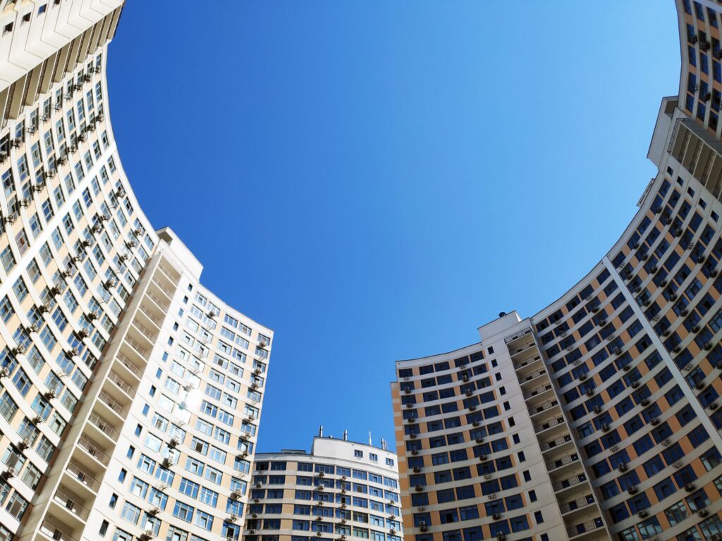 Low angle view of modern high-rise residential buildings under a clear blue sky, representative of Jade Residence in Dubai Silicon Oasis, Dubai