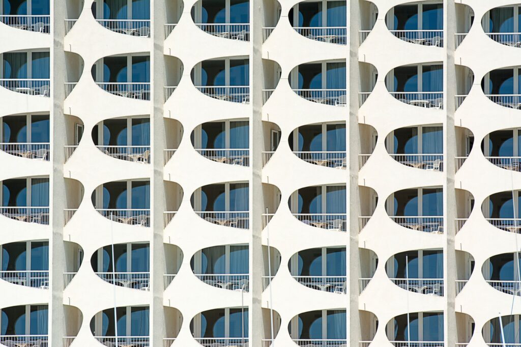 Modern white high-rise building facade with curved balconies and blue glass windows, similar in style to FH Residency, JVT