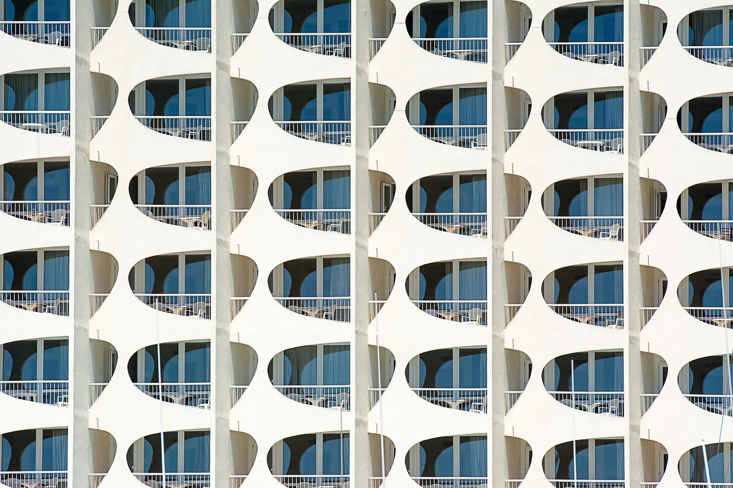 Modern white high-rise building facade with curved balconies and blue glass windows, similar in style to FH Residency, JVT