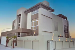 Villa exterior at dusk with stone-clad walls, a roof terrace and a row of garage doors