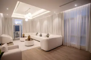 Living room in the villa with curved cream sofas, round coffee tables and sheer curtains