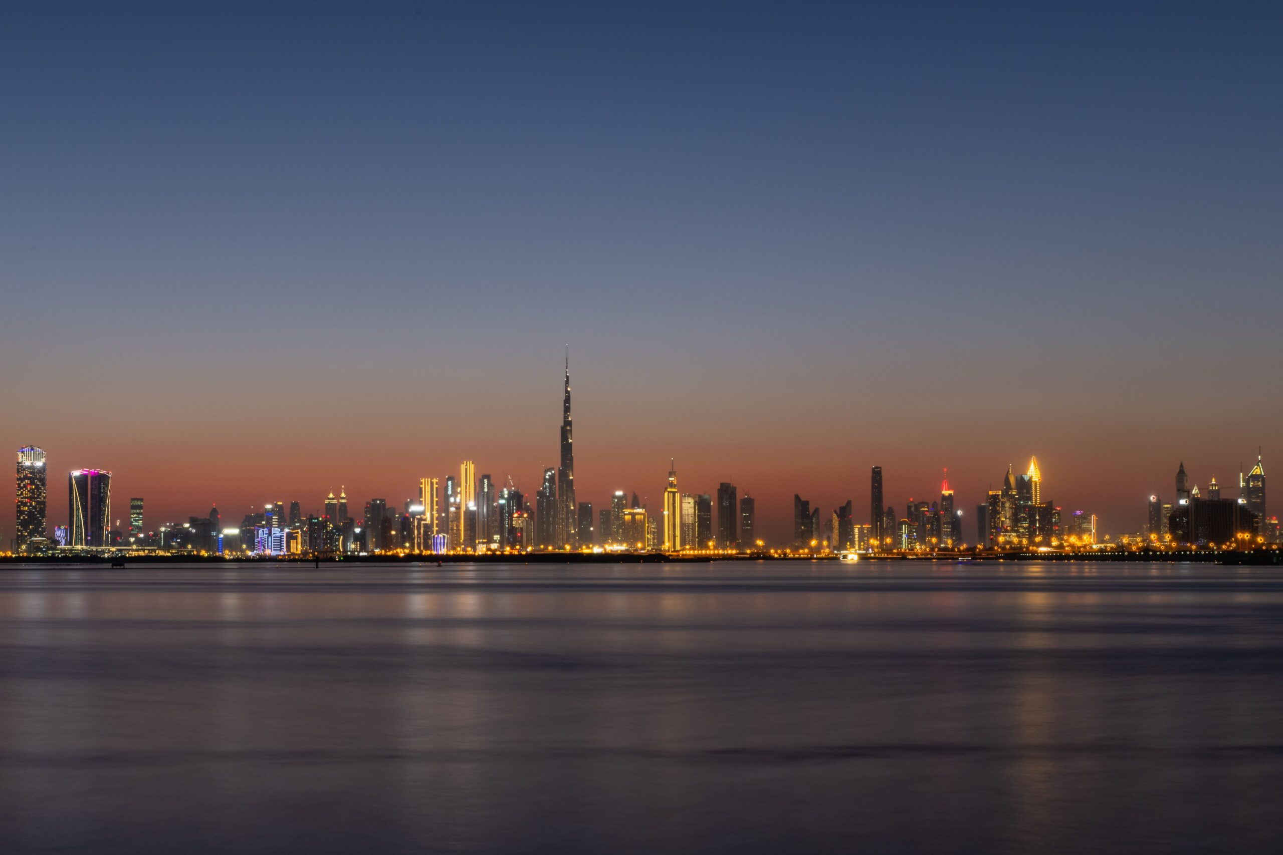 Dubai skyline across the water at dusk with Burj Khalifa