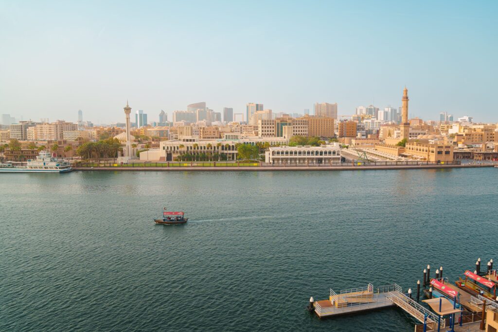 Dubai Creek waterfront with an abra boat and low-rise buildings on the Deira side