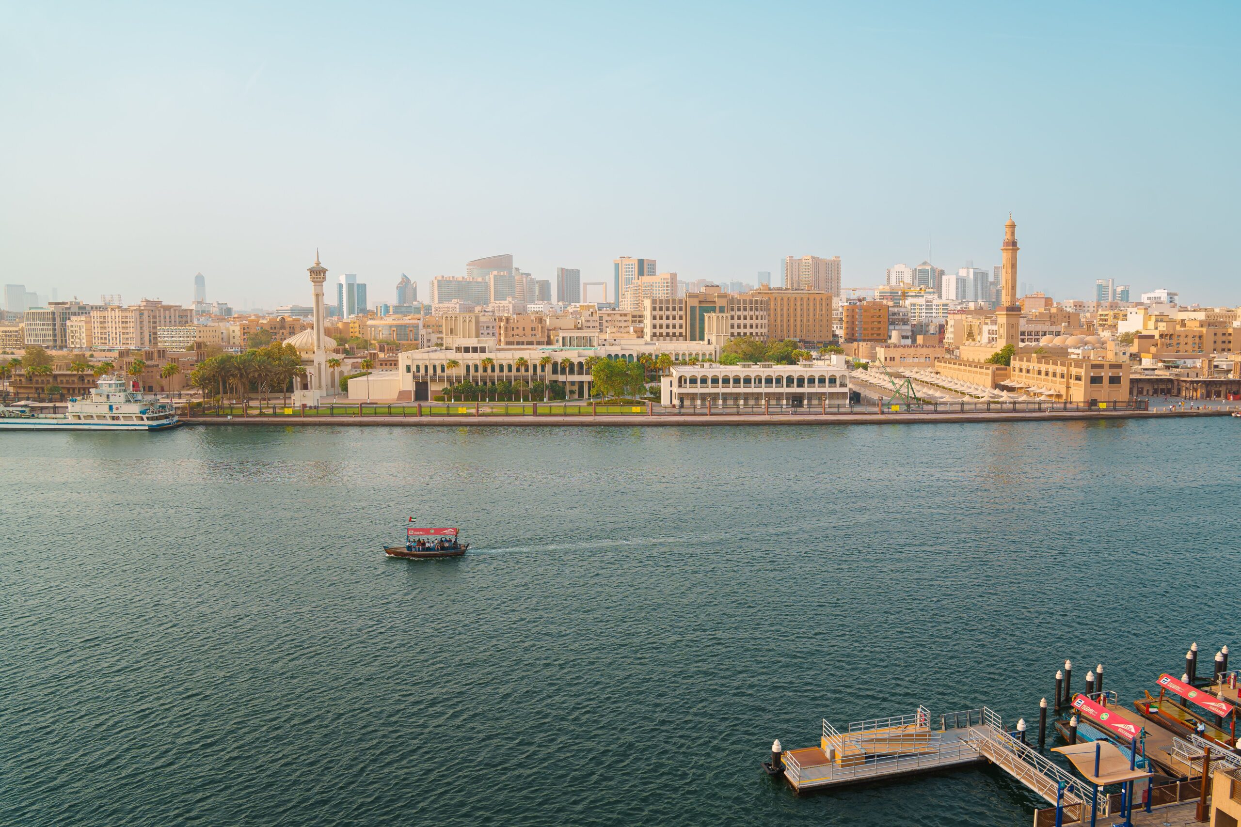 Dubai Creek waterfront with an abra boat and low-rise buildings on the Deira side